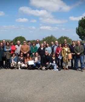 Group photo of a diverse gathering of people standing outdoors in a rural setting. - Olive Oil Times