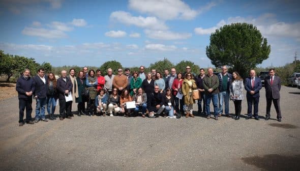 Group photo of a diverse gathering of people standing outdoors in a rural setting. - Olive Oil Times