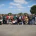 Group photo of a diverse gathering of people standing outdoors in a rural setting. - Olive Oil Times