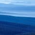 Layered blue mountain landscape featuring rolling hills and valleys in various shades of blue. - Olive Oil Times