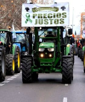 Line of tractors in a protest march displaying a banner that reads 'Precios Justos'. - Olive Oil Times