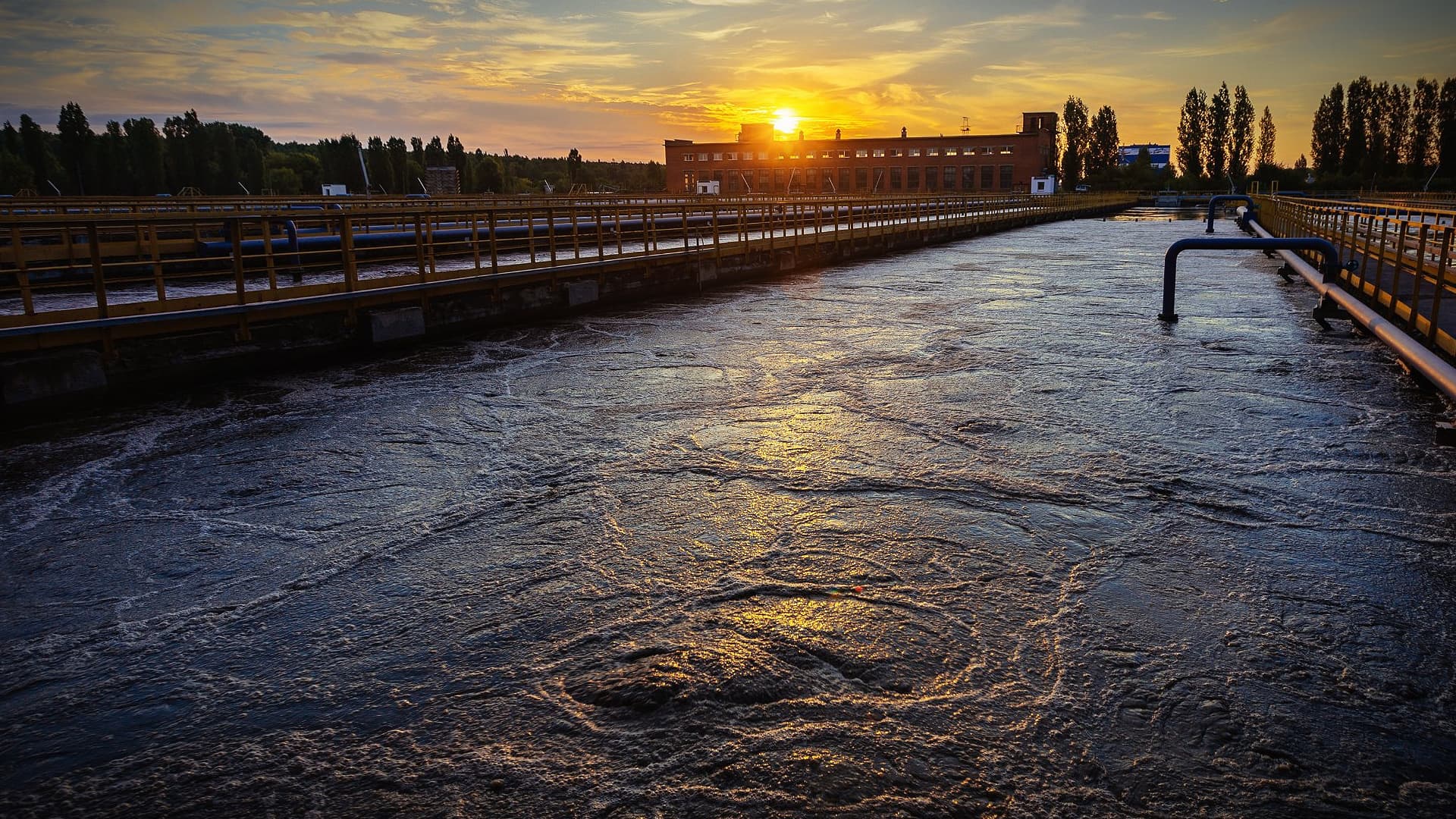 Water treatment facility with a view of the sunset reflecting on the water surface. - Olive Oil Times