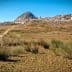 A landscape featuring a hill with a village at its base and dry vegetation in the foreground. - Olive Oil Times