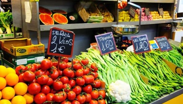 A market display featuring tomatoes, green beans, and other vegetables with price signs. - Olive Oil Times