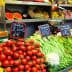 A market display featuring tomatoes, green beans, and other vegetables with price signs. - Olive Oil Times