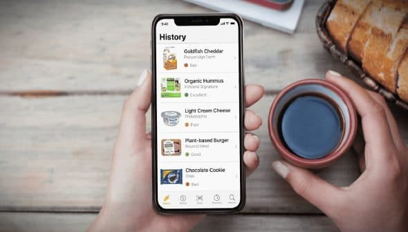 Person holding a smartphone displaying a food review app with various food items and ratings. - Olive Oil Times