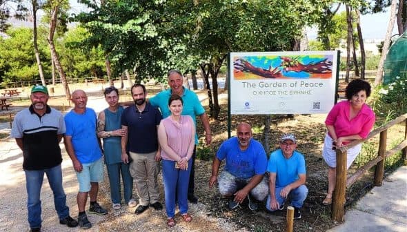 A group of nine individuals posing in front of a sign that reads 'The Garden of Peace'. - Olive Oil Times