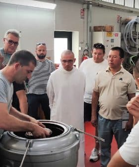 A group of individuals observing a demonstration of the olive oil production process in a facility. - Olive Oil Times