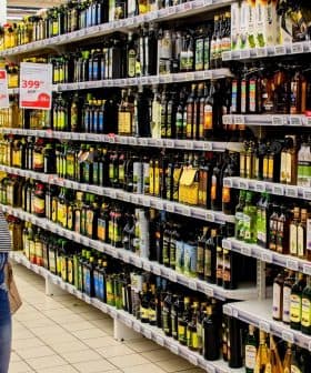 Individual looking at various bottles of olive oil on a supermarket shelf. - Olive Oil Times