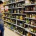 Individual looking at various bottles of olive oil on a supermarket shelf. - Olive Oil Times
