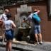 Group of people interacting with a wall-mounted fountain in an outdoor setting. - Olive Oil Times
