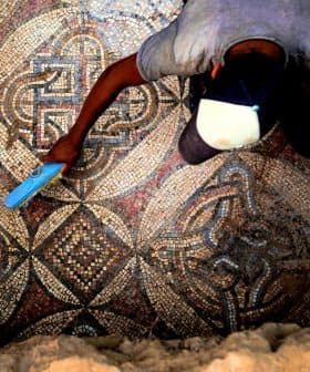 An archaeologist using a tool to clean an intricate ancient mosaic floor. - Olive Oil Times