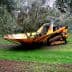 Olive harvesting machine positioned among olive trees in a grove. - Olive Oil Times