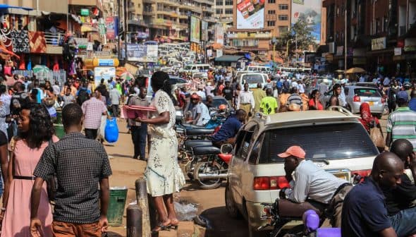 Crowded street in Kampala with pedestrians and vehicles, showcasing daily urban life. - Olive Oil Times