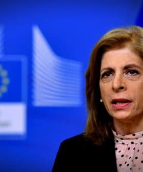 A European Commission official speaking during a press conference with a blue backdrop and the EU flag. - Olive Oil Times