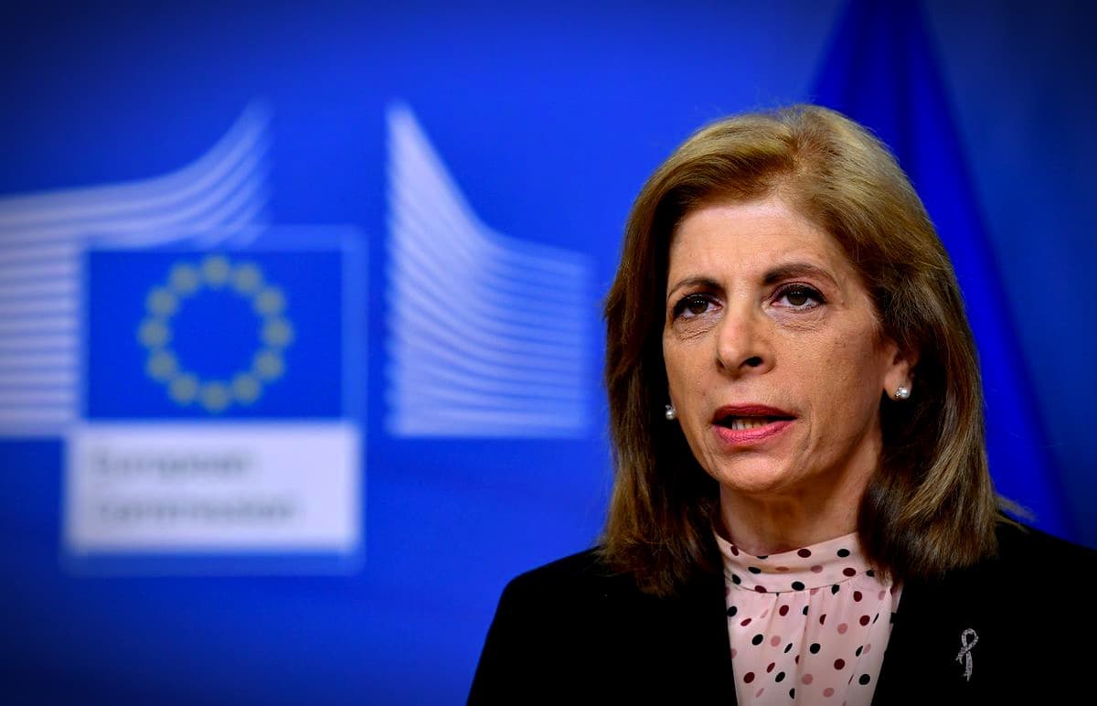A European Commission official speaking during a press conference with a blue backdrop and the EU flag. - Olive Oil Times