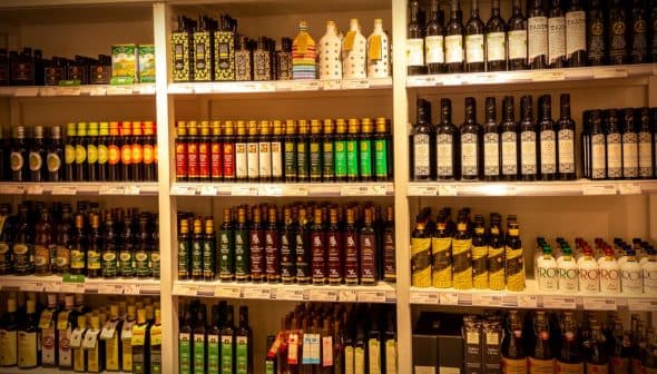 Shelves displaying a variety of olive oil bottles in different shapes and sizes. - Olive Oil Times
