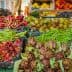 Display of assorted fresh vegetables and fruits including artichokes, green beans, and oranges at a market. - Olive Oil Times