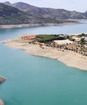 Aerial view of a reservoir with turquoise water and hills in the background. - Olive Oil Times