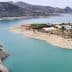 Aerial view of a reservoir with turquoise water and hills in the background. - Olive Oil Times