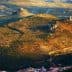 Aerial view of olive groves and hills in a rural landscape with a castle ruin. - Olive Oil Times