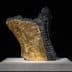 Sculpture featuring a textured black surface with a gold section, displayed on a light base. - Olive Oil Times