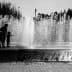 Silhouettes of children playing in a water fountain with water spraying in the background. - Olive Oil Times