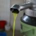 Stream of fresh olive oil flowing from a metal spout during the extraction process. - Olive Oil Times