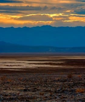 A desert landscape featuring mountains and a sunset with clouds in the sky. - Olive Oil Times