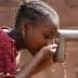 A child drinking water from a tap using cupped hands in a close-up view. - Olive Oil Times
