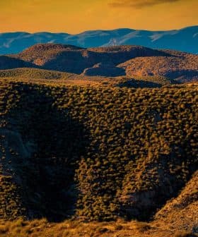 A view of a mountainous landscape featuring rolling hills and vegetation under a sunset sky. - Olive Oil Times