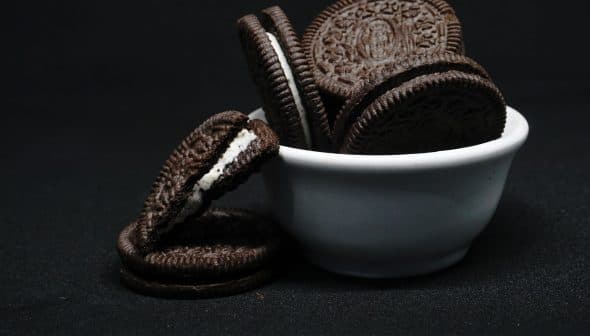 A white bowl filled with Oreo cookies, some cookies stacked and one cookie with cream filling visible. - Olive Oil Times