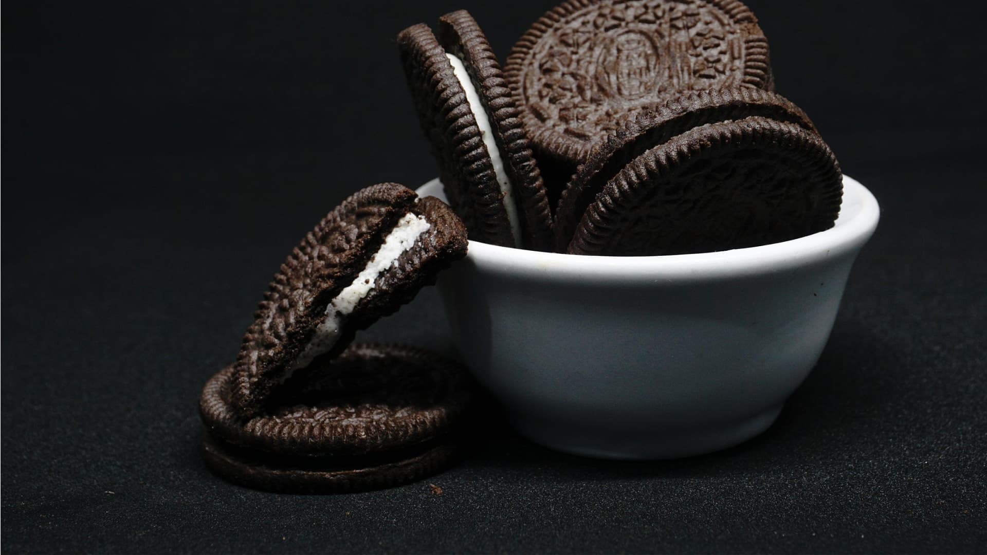 A white bowl filled with Oreo cookies, some cookies stacked and one cookie with cream filling visible. - Olive Oil Times