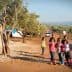 Group of children standing in an olive grove with tents in the background. - Olive Oil Times