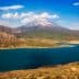 Snow-capped mountain with a clear blue sky above a large lake surrounded by hills. - Olive Oil Times