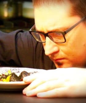 Chef closely inspecting a plate of food with a fork in hand, focused on the dish. - Olive Oil Times
