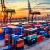 Colorful shipping containers stacked at a port with cranes in the background during sunset. - Olive Oil Times