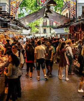 A busy market scene with numerous stalls selling a variety of goods and many people browsing. - Olive Oil Times