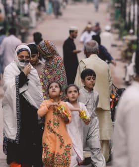 A group of adults and children walking together on a street, some wearing traditional clothing. - Olive Oil Times