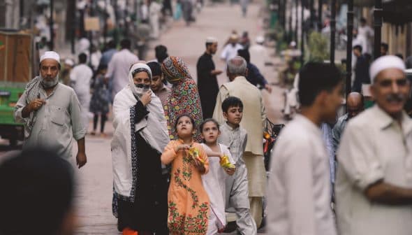 A group of adults and children walking together on a street, some wearing traditional clothing. - Olive Oil Times