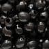 Close-up image of shiny black olives with visible holes. - Olive Oil Times