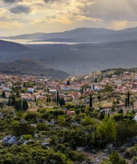 A panoramic view of a village nestled in the mountains with surrounding greenery and hills in the background. - Olive Oil Times