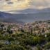 A panoramic view of a village nestled in the mountains with surrounding greenery and hills in the background. - Olive Oil Times