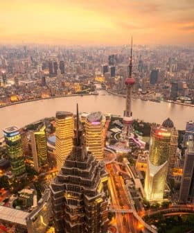 Aerial view of Shanghai's skyline featuring skyscrapers and the Huangpu River during sunset. - Olive Oil Times
