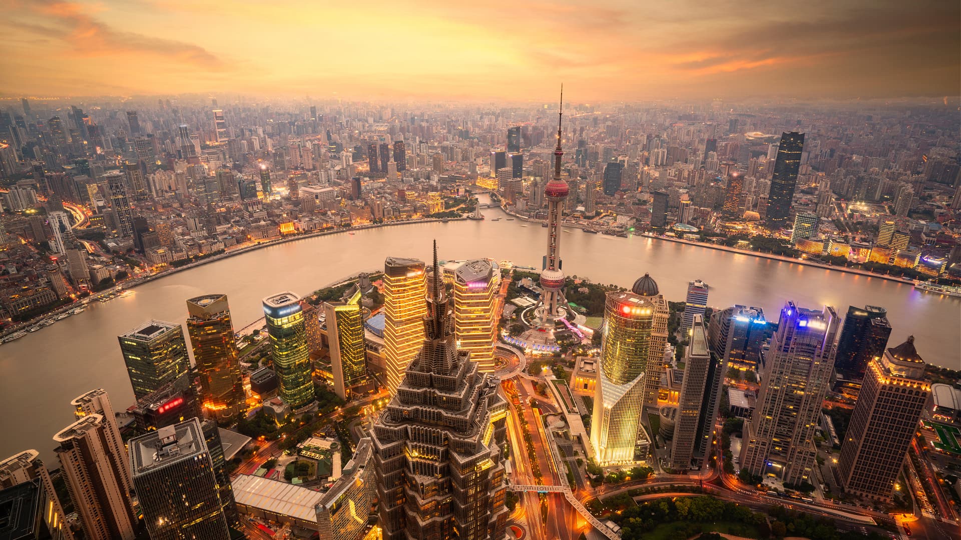 Aerial view of Shanghai's skyline featuring skyscrapers and the Huangpu River during sunset. - Olive Oil Times