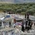 People searching through the rubble of a collapsed building surrounded by olive trees. - Olive Oil Times