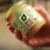 Hand holding a jar labeled with an eco score rating and a green logo. - Olive Oil Times
