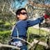 Individual wearing sunglasses and gloves pruning olive trees in a field. - Olive Oil Times