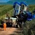 Blue olive harvesting machine positioned on a dirt path in an olive grove. - Olive Oil Times