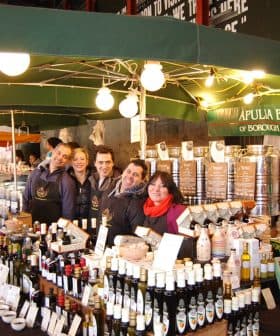 Olive oil stand at Borough Market with staff posing for a photo. - Olive Oil Times